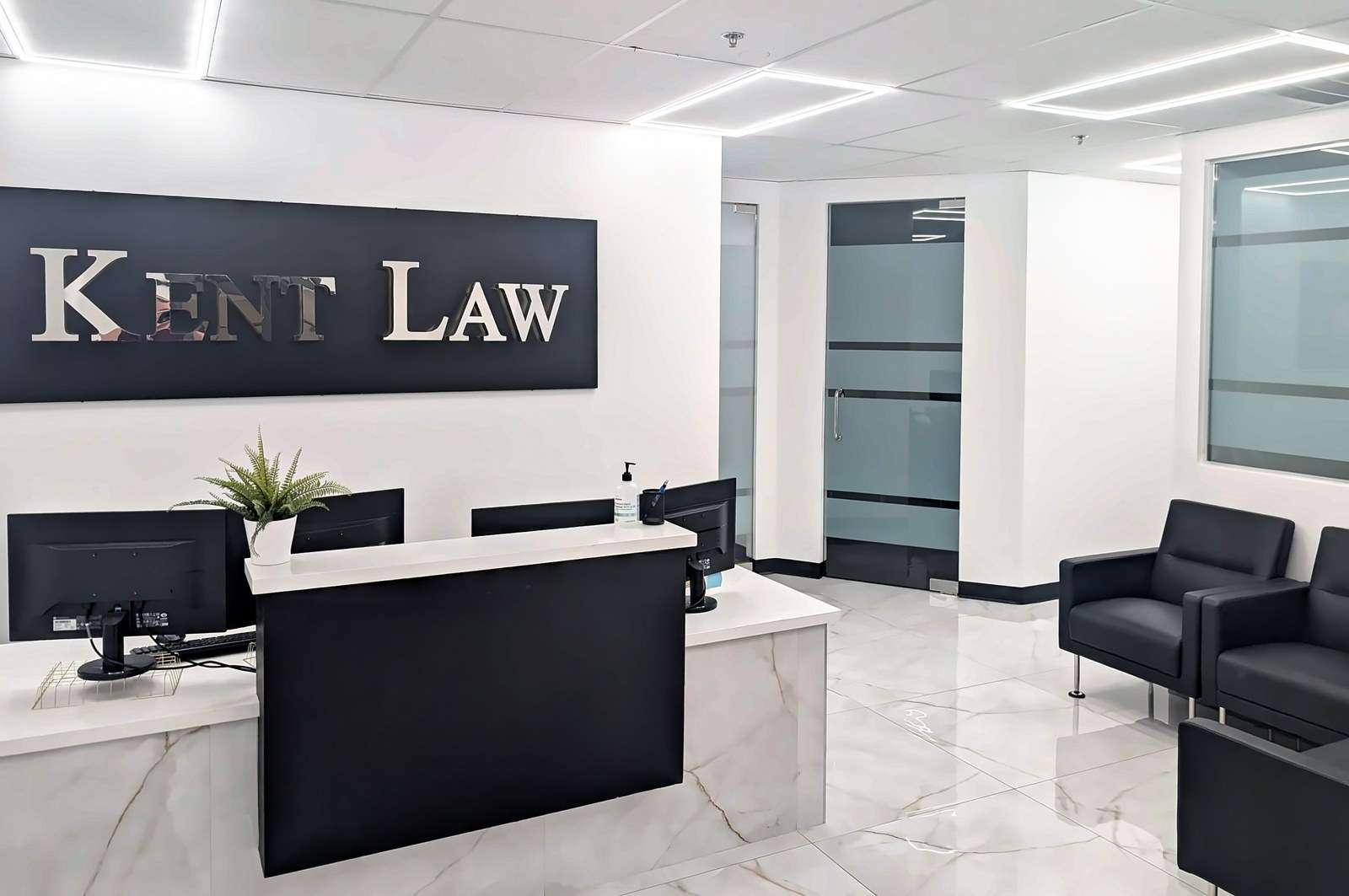Kent Law reception and waiting area in Phoenix with black lounge chairs, the KENT LAW sign and frosted-glass doors